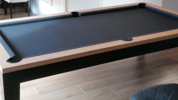 Table de billard à poser sur table avec plateau noir et cadre en bois clair dans une pièce.