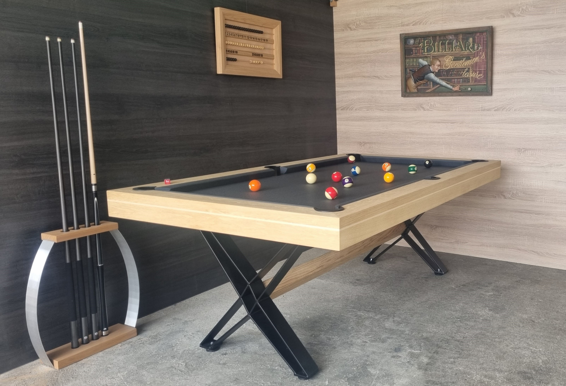 Table de billard moderne avec plusieurs queues appuyées contre le mur et billard prêt à jouer dans une salle décorée.